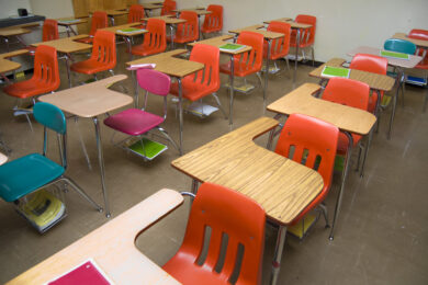 Empty classroom of student desks with colorful chairs.