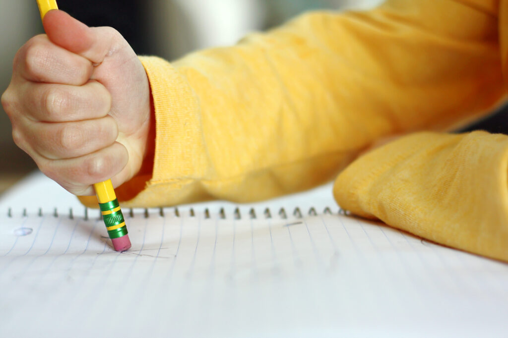 Frustrated child erasing writing.