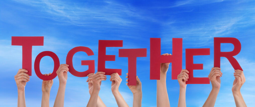 Image shows hands holding up red letters that spell the word together against a blue sky background to signify support in teacher self-reflection.