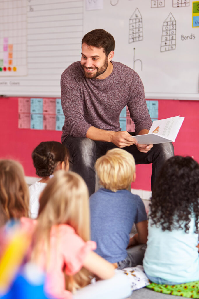 Male teacher reading aloud to class for integrated literacy instruction.