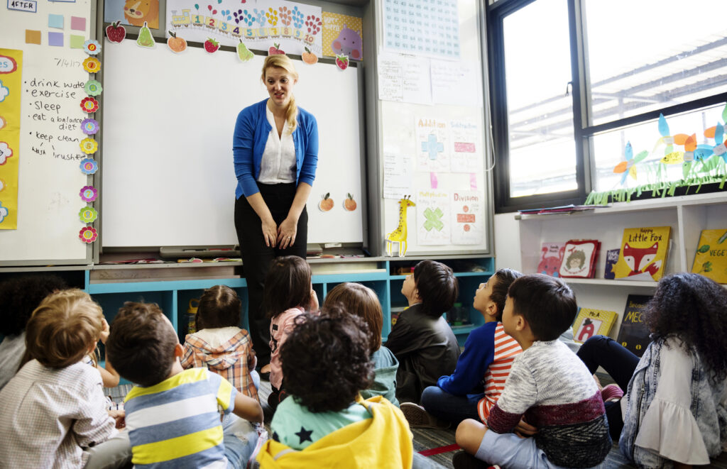 Teacher standing in front of group of students using explicit literacy instruction.