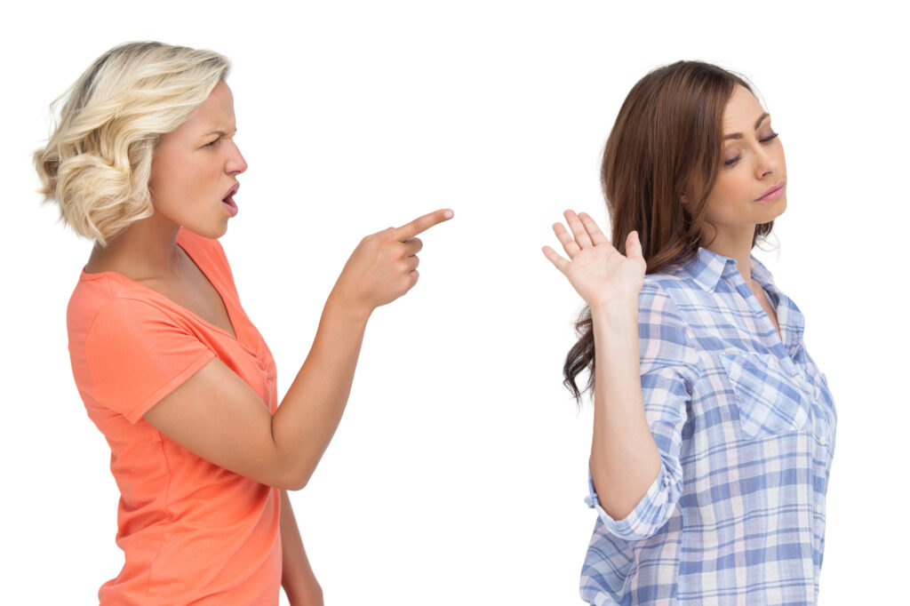 Woman with short blonde hair in orange shirt angrily pointing finger at woman with long brown hair in plaid shirt with hand up and caption that reads arguments about reading instruction are prevalent.