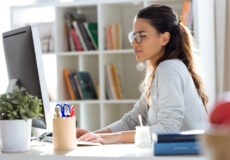 Image shows young female teacher planning lessons at computer.
