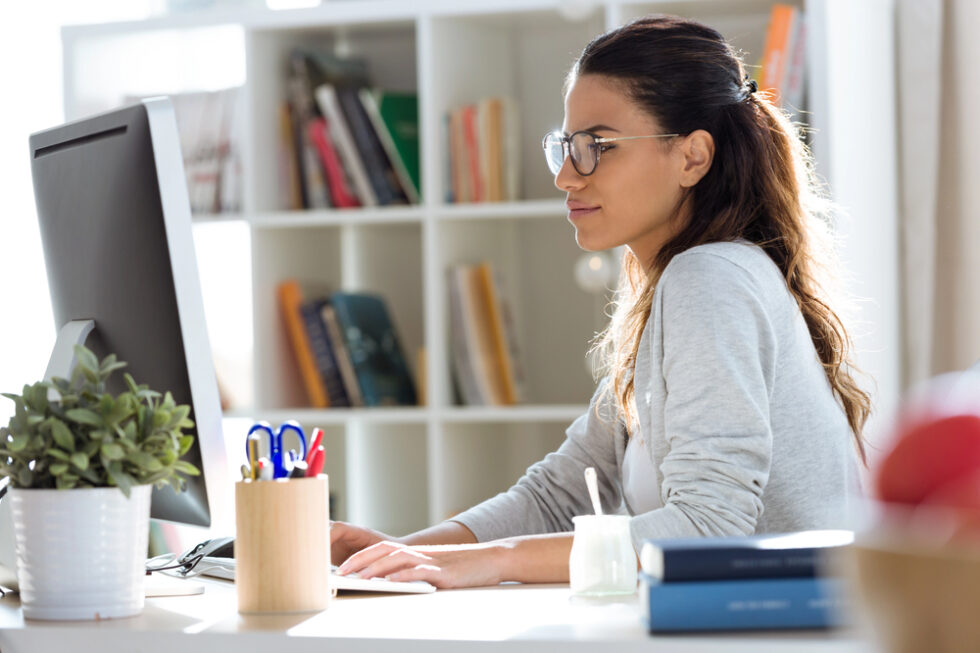 Image shows young female teacher planning lessons at computer.